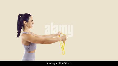 Formation de femme en forme avec bande de résistance jaune, vue latérale sur l'espace de copie beige Banque D'Images
