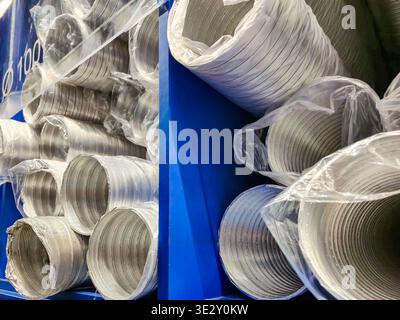 vue rapprochée de nombreux conduits en aluminium flexible ondulé brillants, soigneusement empilés et enveloppés individuellement dans une feuille de plastique transparent dans un Banque D'Images