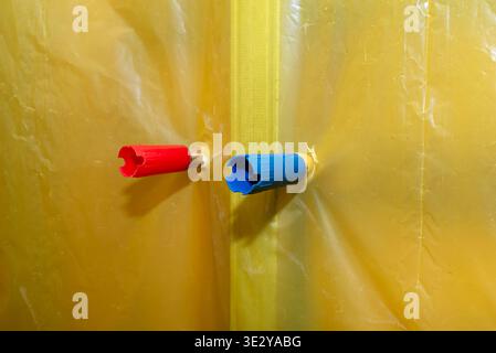 Tuyaux d'eau chaude et froide pénétrant dans un pare-vapeur jaune pendant la construction Banque D'Images
