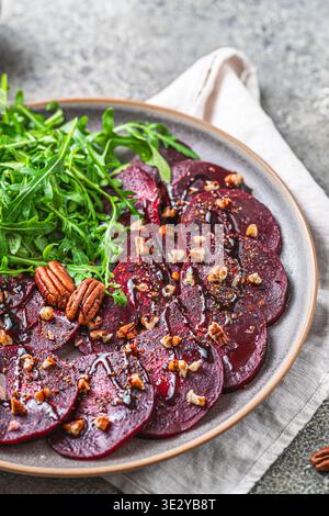 Carpaccio de betterave avec glaçage balsamique et salat de roquette sur fond rustique gris, vertical Banque D'Images