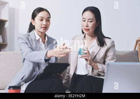 Deux femmes d'affaires ont une réunion productive au bureau. Ils discutent de questions commerciales, signent un contrat et se serrent la main Banque D'Images
