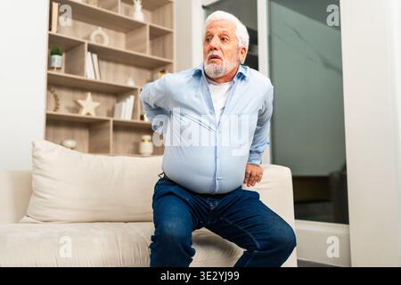 Mal de dos mal de dos. Vieil homme âgé malheureux souffrant de mal de dos à la maison. Contrarié l'homme âgé ressent une douleur dorsale soudaine douleurs musculaires douleur tension blessure. Triste grand-père ressentant une douleur dans le dos touchant la colonne vertébrale Banque D'Images