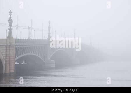 Pétersbourg, Russie. 20 mars 2026. Le pont de la Trinité vu pendant le brouillard matinal. La ville est entourée de brouillard depuis le soir du 19 mars. La brume a persisté jusqu'au matin. Le ministère régional des situations d'urgence a averti de la détérioration des conditions météorologiques la veille. La visibilité a chuté à 500 mètres, augmentant le risque d'accidents de la circulation dans la ville. Crédit : SOPA images Limited/Alamy Live News Banque D'Images