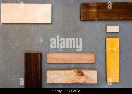 Pose à plat de diverses pièces de bois et de contreplaqué sur texture de béton. Arrière-plan de menuiserie. Banque D'Images