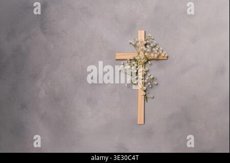 Croix chrétienne en bois décorée de fleurs blanches fraîches de gypsophila. Un symbole religieux de foi, de résurrection et de copyspace du souvenir pour pâques Banque D'Images