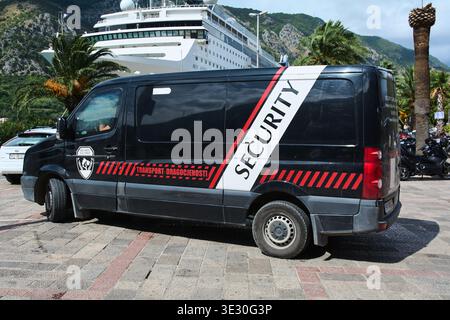 Kotor. Monténégro - 20 mars 2026 : fourgon de sécurité noir garé au port de Kotor avec un grand bateau de croisière blanc amarré en arrière-plan n Banque D'Images
