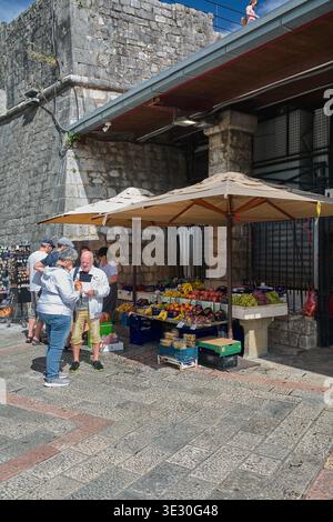 Kotor. Monténégro - 20 mars 2026 : des vendeurs de marché de rue locaux vendent des fruits méditerranéens frais et des collations traditionnelles aux visiteurs en dehors de l'anci Banque D'Images