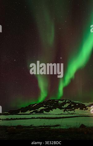 Aurora Borealis illuminant un paysage de montagne enneigé la nuit Banque D'Images