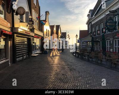 Maisons hollandaises traditionnelles colorées bordant une rue pittoresque, capturées dans la lumière chaude du lever ou du coucher du soleil. L'architecture charmante dans des couleurs vibrantes. Banque D'Images
