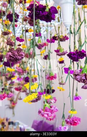 Table de réception de mariage magnifiquement stylée avec verrerie violette texturée, couverts dorés et petits centres-pièces fleuris délicats. Banque D'Images
