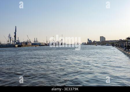 Hambourg Norderelbe anabranch et la zone portuaire avec beaucoup de grues de fret. Eau calme dans la rivière pendant la soirée. Banque D'Images