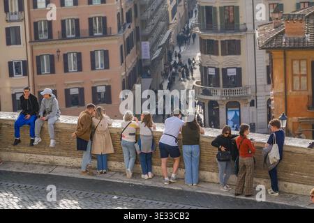Un groupe de touristes divers regardent vers le bas sur le quartier animé de la via Condotti près de la place d'Espagne à Rome, en Italie. Magasins de luxe remarquables visibles. Banque D'Images