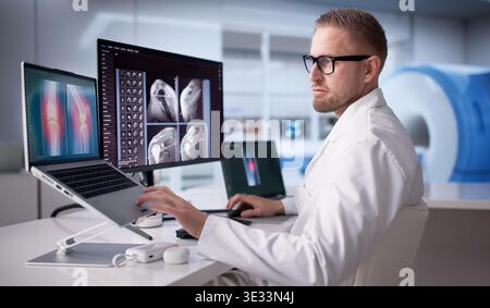 Spécialiste orthopédique analyse les radiographies de l'épaule sur ordinateur portable dans le cabinet médical Banque D'Images