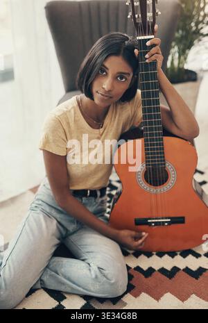 Portrait, musicien et femme avec guitare au sol pour la musique, chanson et piste pour le son acoustique. Maison, artiste et personne avec instrument de musique pour Banque D'Images