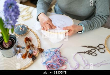 Fille brodant sur tissu étiré dans Un cerceau, Une activité créative, avec Un gros plan des mains Banque D'Images