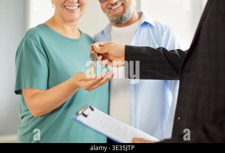 Agent immobilier remettant les clés de la maison au couple mature souriant lors de la fermeture Banque D'Images