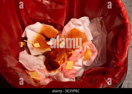 Gros plan de gaze médicale usagée et de bandages tachés de sang jetés dans un sac poubelle rouge à risque biologique. Concept de gestion des déchets de soins de santé, hygiène, Banque D'Images