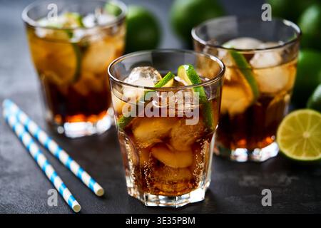 Cocktail cuba libre avec rhum brun, cola et citron vert dans un verre sur une table sombre. Cocktail de thé glacé Cuba libre ou long Island. Banque D'Images