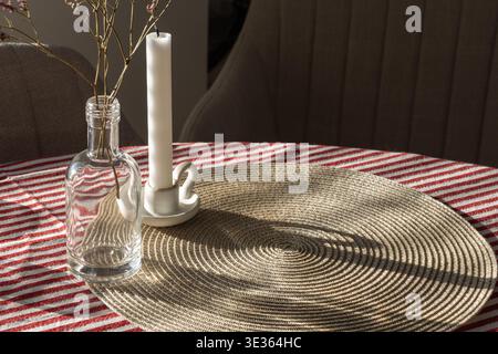 Espace vide arrière-plan. Une table confortable avec un napperon tissé, une bouteille en verre et une bougie dans un support Banque D'Images