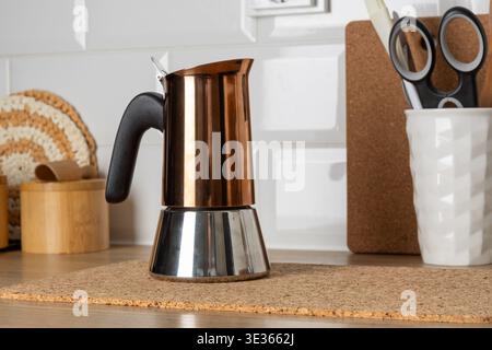 Machine à expresso en cuivre et acier inoxydable placée sur un tapis de liège sur un comptoir en bois. Fond de cuisine lumineux avec mur de carreaux blancs crée un propre, m Banque D'Images