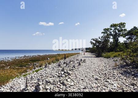 Champ de gravats, plage rocheuse, littoral avec sentier de randonnée sur l'île de Stora Grunddet, promeneurs à l'horizon, mer Baltique, Oeland, Kalmar laen, Suède Banque D'Images