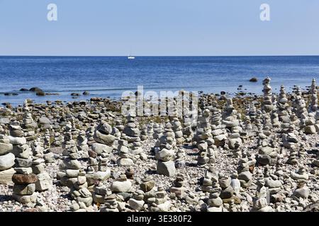 Champ de gravats, plage rocheuse, littoral sur l'île de Stora, voilier à l'horizon, pile de pierre, hommes de pierre, mer Baltique, Oeland, Kalmar Laen, Suède Banque D'Images