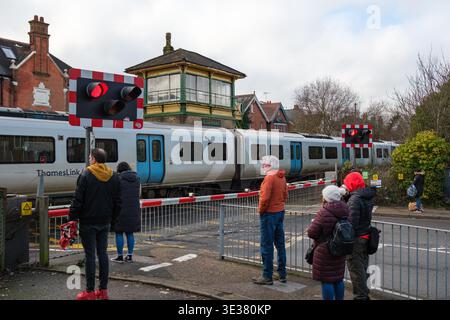 Les gens attendent au passage à niveau du chemin de fer à Crawley Brighton Road, qui abrite la boîte de signalisation victorienne de catégorie deux, comme passe un train Thames Link. Banque D'Images