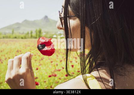 Portrait femme sent les fleurs de pavot au printemps dans le village de marneuli, Géorgie Banque D'Images