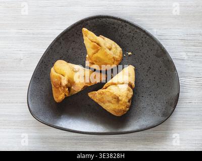 La cuisine indienne - Samosa de légumes poêlée de feuilletage de pois verts et les pommes de terre sur la plaque noire sur la table en bois Banque D'Images
