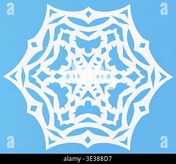 Flocon de neige blanc coupé à la main sur papier bleu Banque D'Images