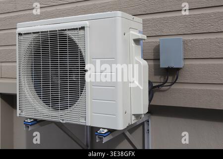 Thermopompe de climatisation (condenseur) et boîte de déconnexion électrique (interrupteur de sécurité externe) montées sur le mur extérieur de la maison, Québec, Canada Banque D'Images