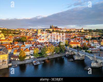 Au petit matin, la lumière du soleil se répand sur les toits de Prague, mettant en évidence l'emblématique pont Charles et le majestueux château de Prague en arrière-plan, le long de la rivière Vltava. Banque D'Images