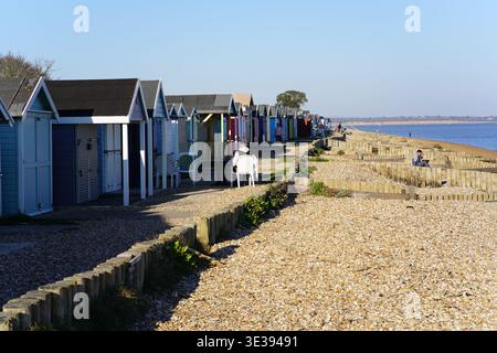 Rangée de cabanes de plage traditionnelles colorées bordant la plage de galets de Calshot sur le Solent, Hampshire, Angleterre. Banque D'Images