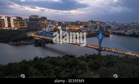 Hyderabad, INDE - 21 JUIN 2025 paysage urbain d'Hyderabad au crépuscule avec le pont câblé de Durgam Cheruvu au-dessus du lac, entouré de bâtiments modernes Banque D'Images