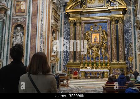 Basilique papale di Santa Maria Maggiore. Rome, Italie. Autel baroque avec icône de la Madone dorée, marbre riche et statues. Touristes observant quietl Banque D'Images
