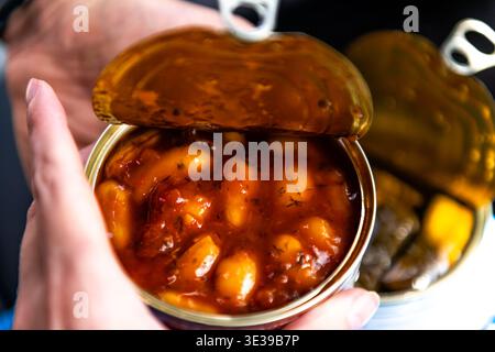 Les haricots cannellini géants cuits au four dans la sauce tomate peuvent être stockés comme apéritif végétalien grec avec des herbes tenant la main comme collation Banque D'Images
