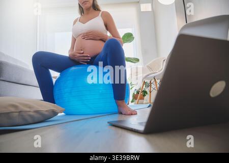 Future mère faisant des exercices prénataux sur une boule de stabilité, balançant doucement ses hanches Banque D'Images