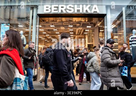 Les consommateurs marchent devant la vitrine Bershka sur Oxford Street, dans le centre de Londres, alors que l'économie britannique reste lente et que l'inflation devrait à nouveau augmenter. Banque D'Images