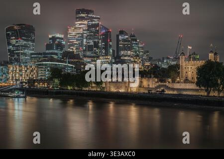 La Tour de Londres illuminée la nuit avec les gratte-ciels modernes de la City de Londres derrière Banque D'Images