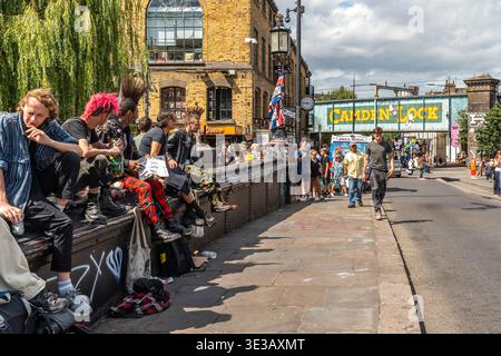 Punks assis sur un pont à Camden Town près de l'emblématique panneau ferroviaire Camden Lock, Londres Banque D'Images