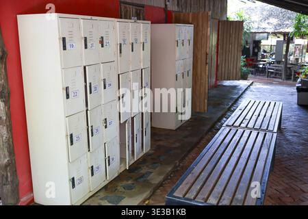 Vestiaire calme et vide avec armoires de rangement blanches et long banc en bois. vestiaire rustique à l'école ou au gymnase offre un endroit paisible pour la sécurité Banque D'Images