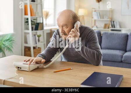 Homme ayant quelques problèmes avec le signal tout en essayant de faire un appel via un téléphone fixe Banque D'Images