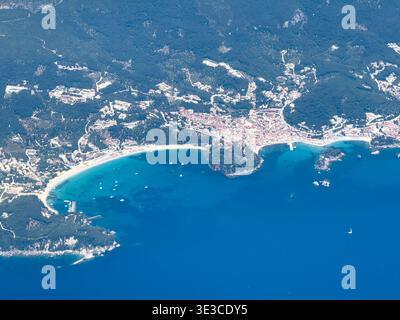 Ville de Parga et plage de Valtos dans le nord-ouest de la Grèce. Vue aérienne depuis la fenêtre plane. Eaux turquoises, bateaux ancrés et collines verdoyantes Banque D'Images