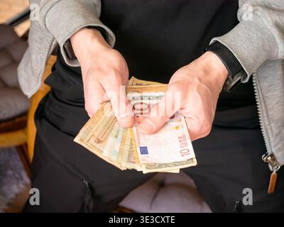 Homme comptant le papier-monnaie en main. Personne détenant divers billets, y compris en euros. Concept financier, paiement en espèces, épargne, banque, budget Banque D'Images