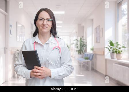 médecin debout dans le couloir de l'hôpital tenant des documents représentant le professionnalisme des soins de santé et l'environnement clinique Banque D'Images
