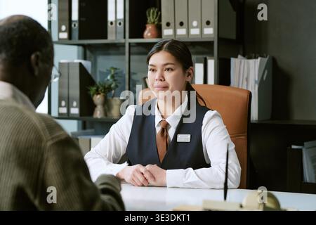 Jeune femme asiatique adulte aidant homme noir senior lors de la consultation bancaire Banque D'Images