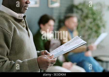 Homme noir d'âge moyen tenant des documents pendant qu'il attendait à l'intérieur de la succursale bancaire Banque D'Images