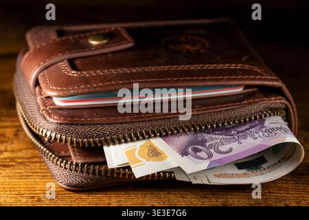 Gros plan de billets britanniques de 20 GBP dans un portefeuille en cuir marron sur une surface en bois. Concept de finance, d'épargne et de monnaie britanniques. Banque D'Images
