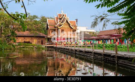 Chiang mai, Thaïlande – 3 mars 2020 : le temple Wat Chet Lin et une passerelle en bois avec des parapluies colorés se reflètent dans un étang sur le terrain du temple. Banque D'Images