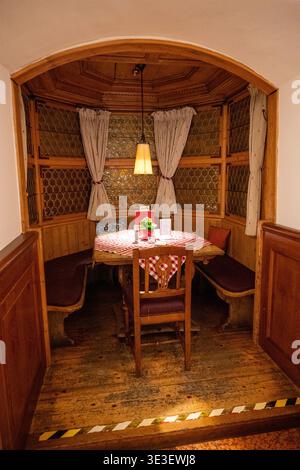 Munich, Allemagne - 29 mars 24 : cabine en bois intime à Munich Ratskeller avec des panneaux sculptés, du verre à motifs, des rideaux et un petit ensemble de table Banque D'Images